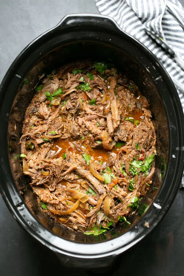 Finished shredded barbacoa beef in a slow cooker.