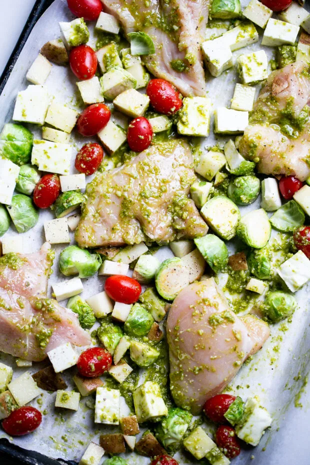 Chicken and vegetables covered in basil pesto ready for the oven.