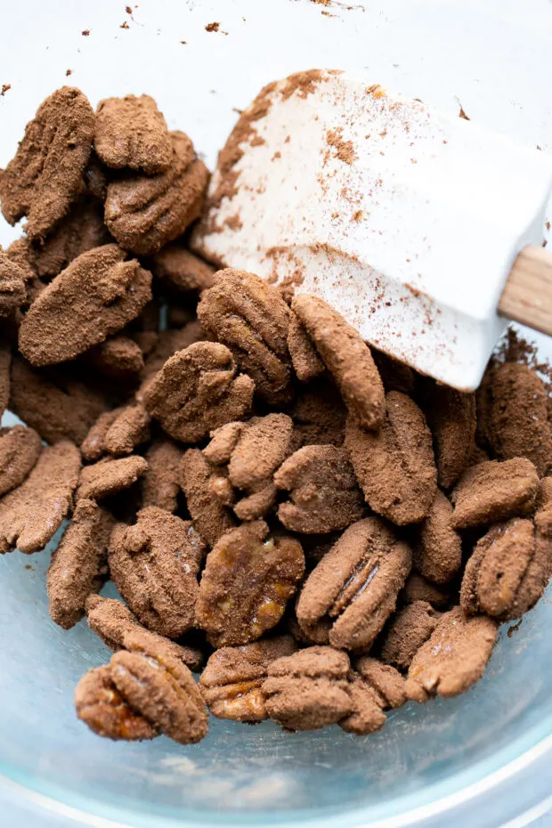 Freshly glazed pecans being tossed in the cocoa mixture with the white rubber spatula.