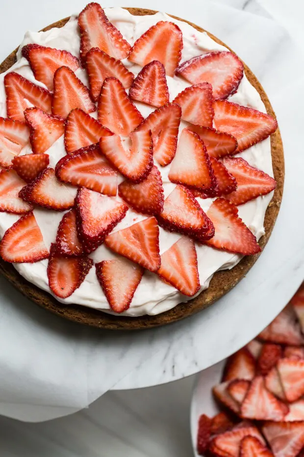 Cake layer topped with strawberry butter cream and sliced fresh strawberries.
