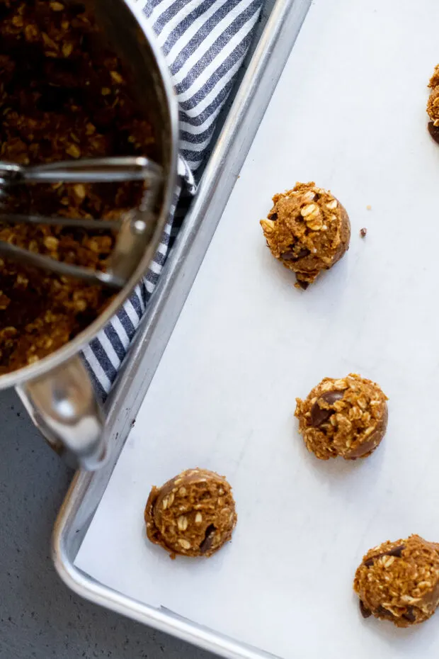 Parchment lined baking sheet with scoops of cookie dough ready to bake.