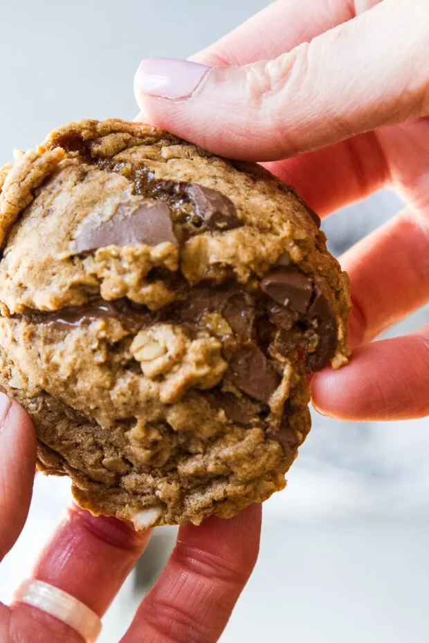 Freshly baked peanut butter oatmeal cookie with oozy chocolate. Cookie is held in my hands and being split apart.