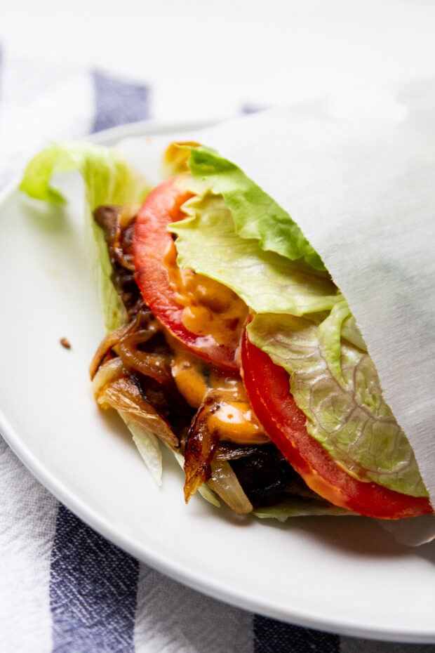 Another view of the smash burger wrapped in a lettuce bun and parchment paper.