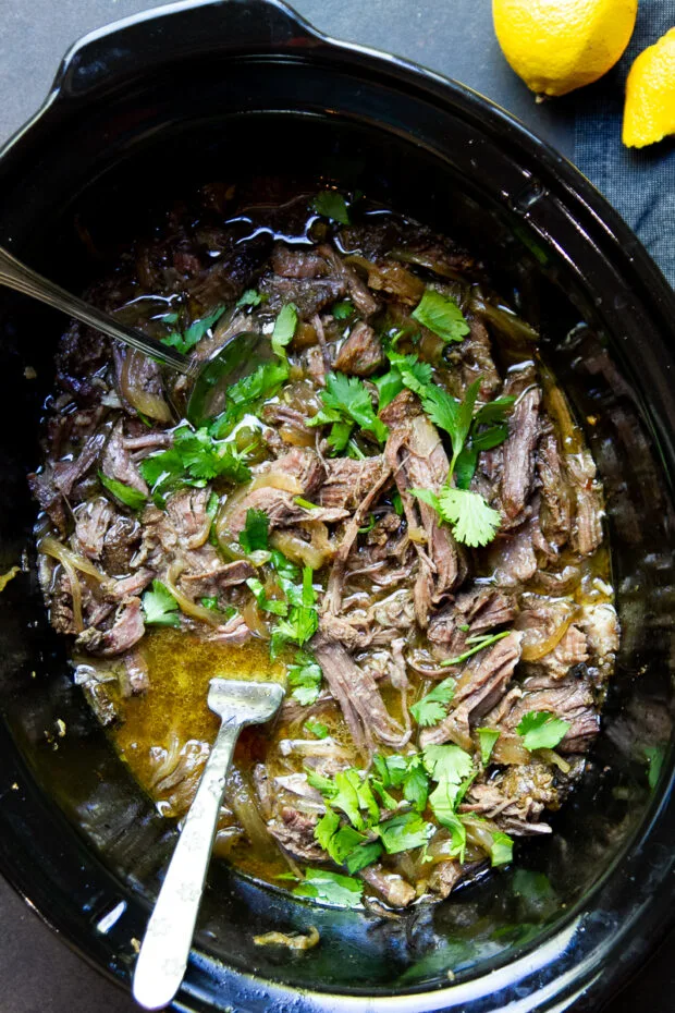 Gyro-inspired shredded beef shredded in the slow cooker and topped with fresh cilantro.