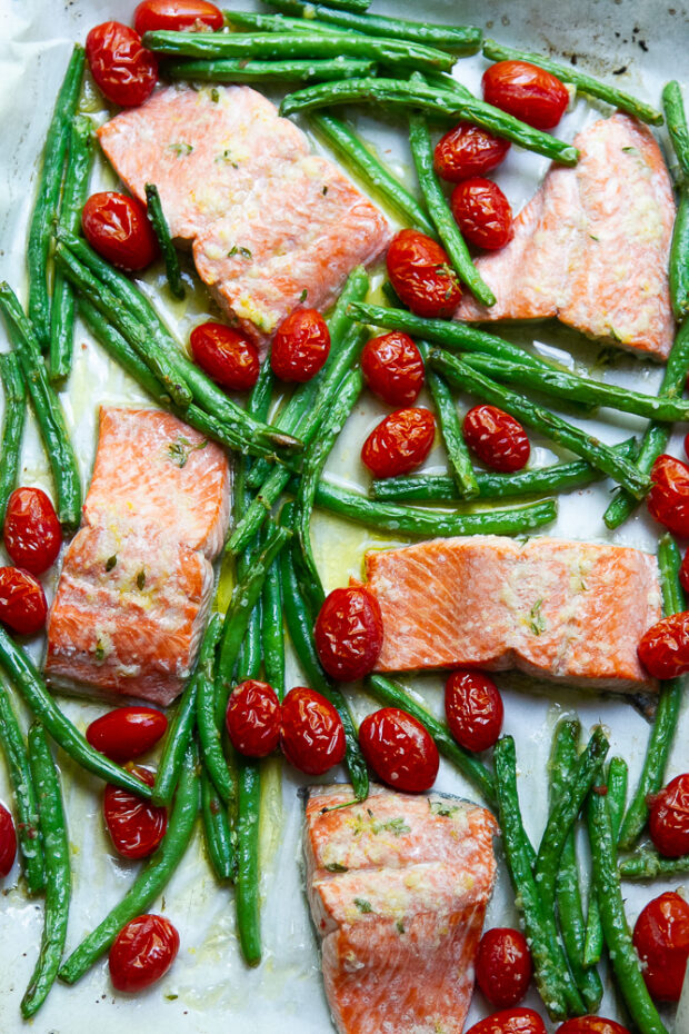 Garlic Butter Sheet Pan Salmon roasted with grape tomatoes and green beans on a parchment lined baking sheet.