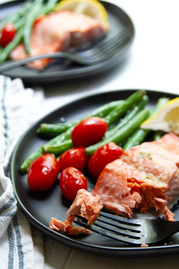 Broiled salmon and vegetables on servings plates ready to eat.