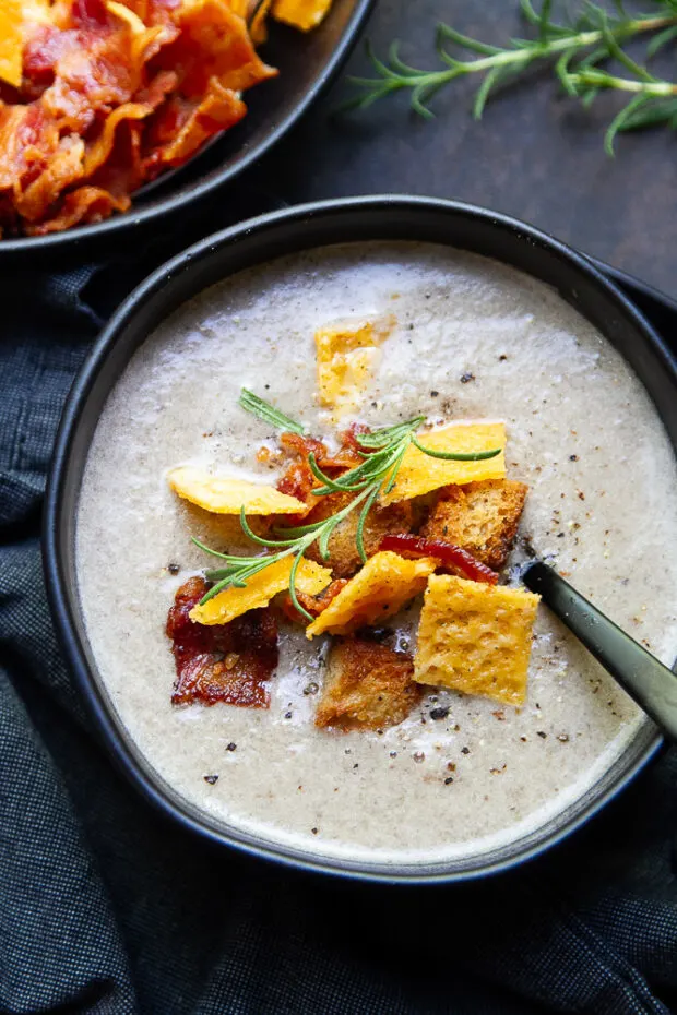 Finished mushroom soup in a black bowl with garnishes.