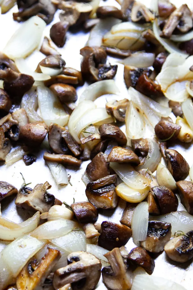 Rimmed baking sheet with roasted mushrooms, garlic, & onion.