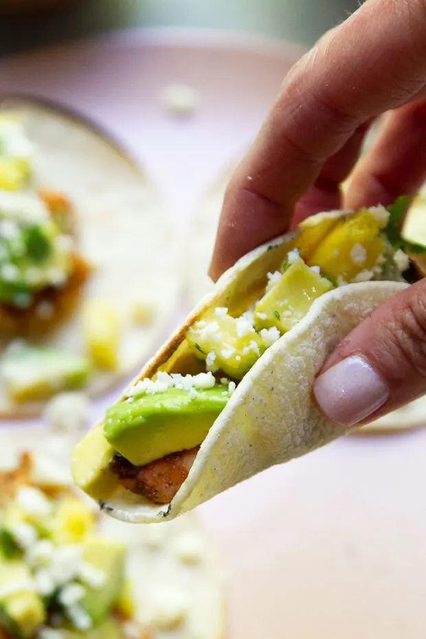 View of a hand picking up a taco ready to eat.