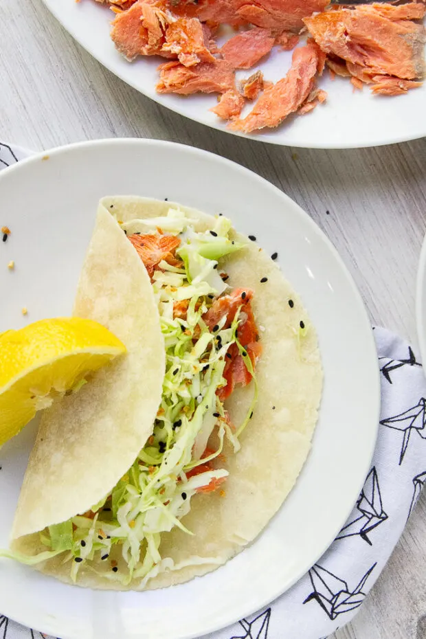 Smoked Salmon taco on a white plate with a lemon wedge for garnish.