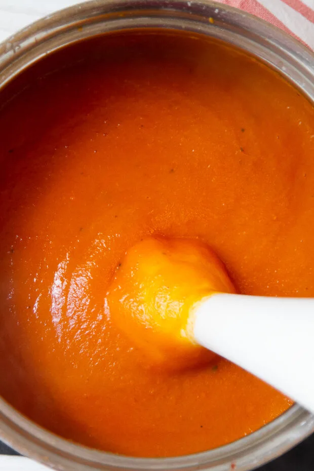 Freshly blended pasta sauce. Immersion blender is sticking out of the saucepan.