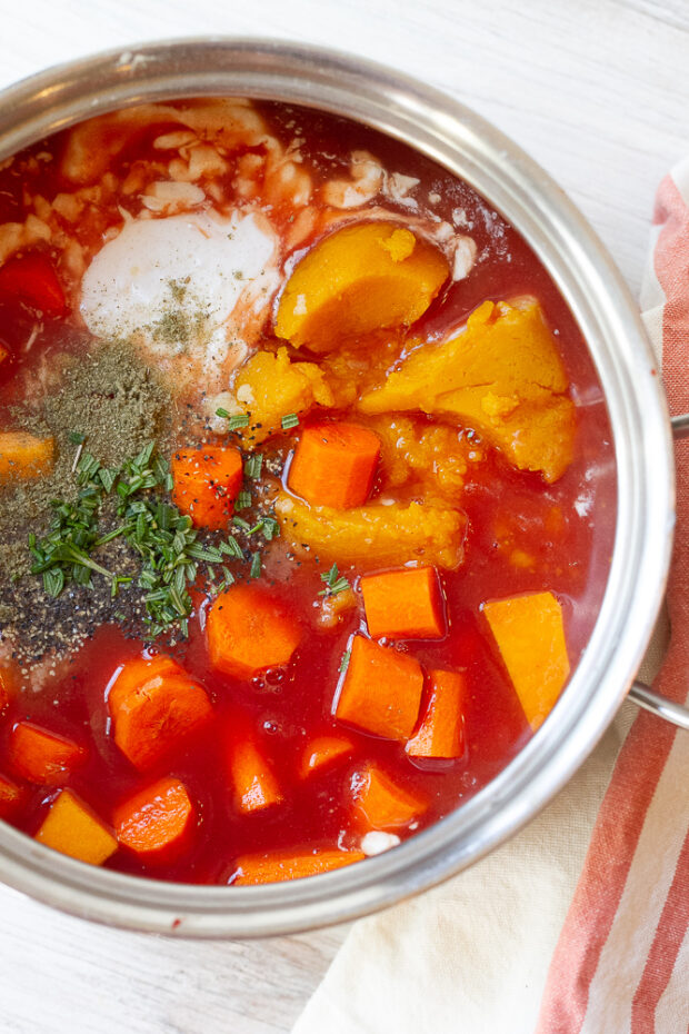 Saucepan with uncooked ingredients for butternut squash pasta sauce -- pumpkin puree, butternut squash cubes, carrots, coconut milk, fresh rosemary, etc.