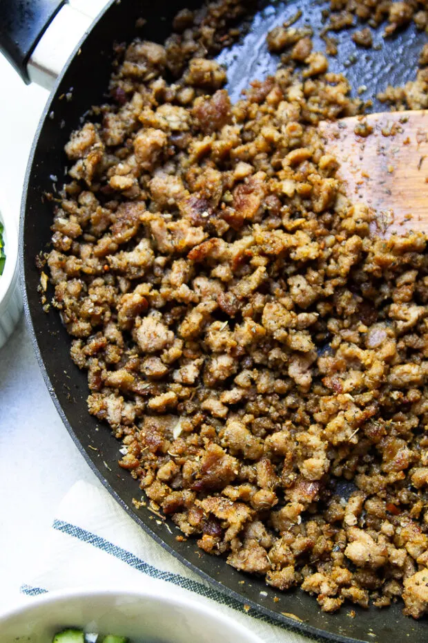 Crispy, seasoned ground turkey in a skillet with a wooden spatula.