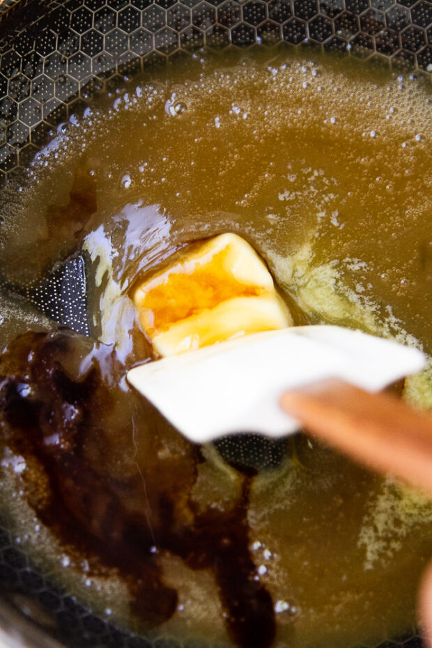 A pat of butter added to the maple glaze in a small skillet.