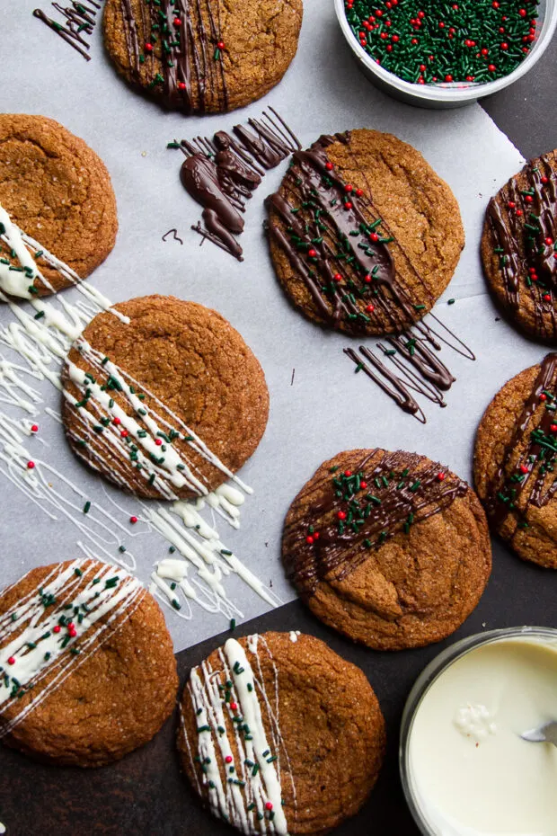 Another shot of ginger molasses cookies on parchment drizzled with different kinds of chocolate.