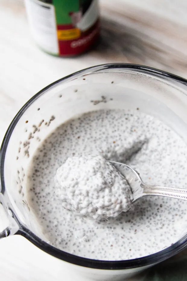 Coconut Chia Pudding after it has been chilled overnight. A spoonful is being scooped out and you can see that is has thickened considerably.