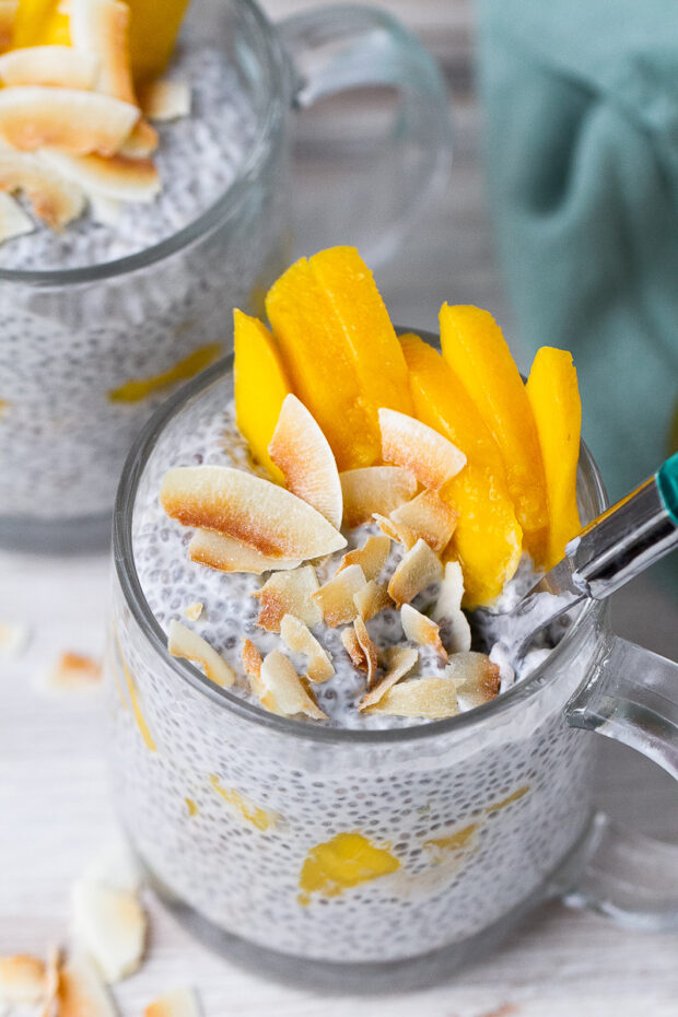 Another view of the chia pudding ready to eat with a spoon inserted into the mug.