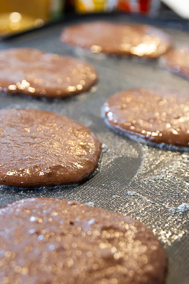Rounds of paleo pancake batter cooking on a nonstick griddle.