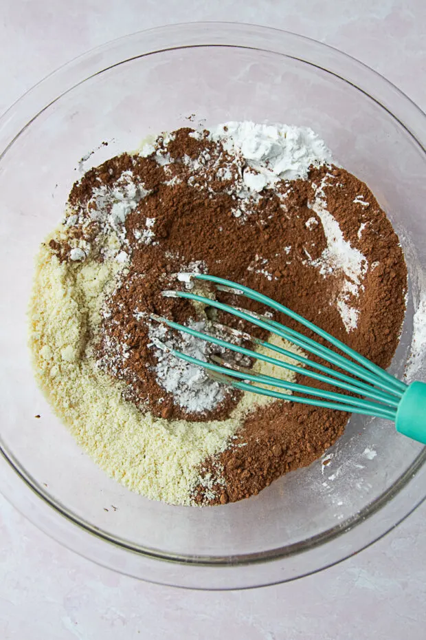 Clear bowl with dry ingredients for paleo pancakes -- almond flour, tapioca flour, cocoa powder, baking soda, & salt.