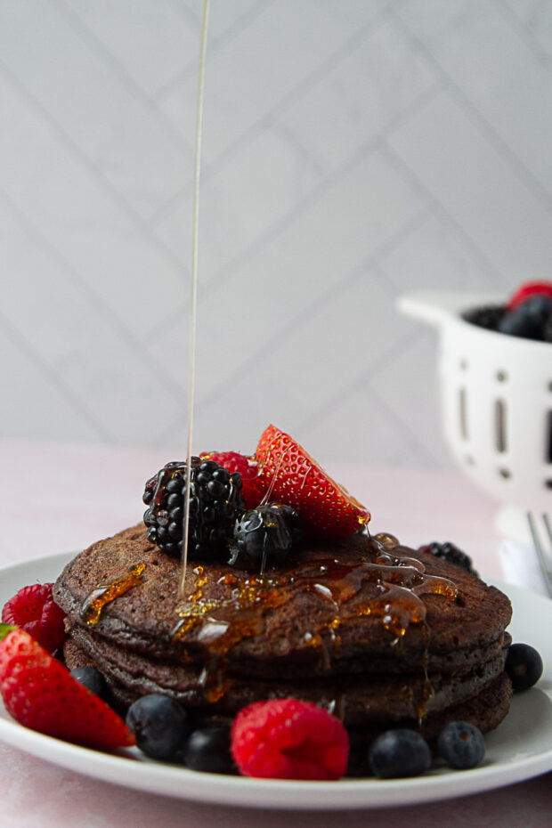 That same stack of pancakes is topped with fresh strawberries, raspberries, and blackberries and actively drizzled with honey.