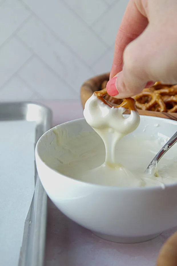 Pretzel twist being dipped in white chocolate.