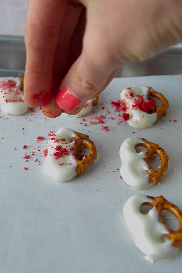 Sprinkling some freeze dried strawberry powder on the wet dipped pretzels.