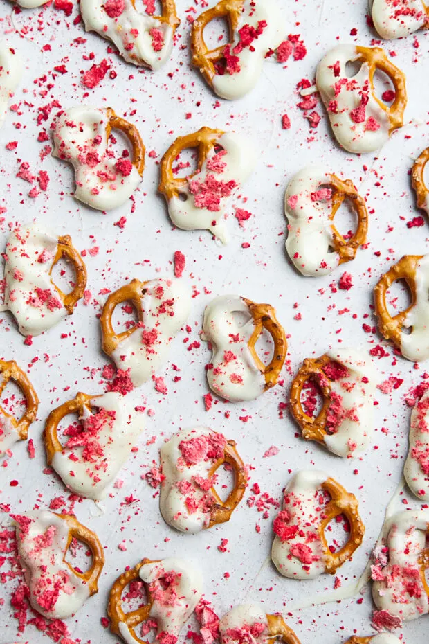 Strawberry White Chocolate Pretzels drying on parchment.
