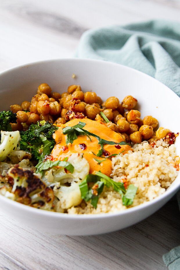 Quinoa bowl with roasted vegetables, roasted red pepper sauce, and fresh basil.
