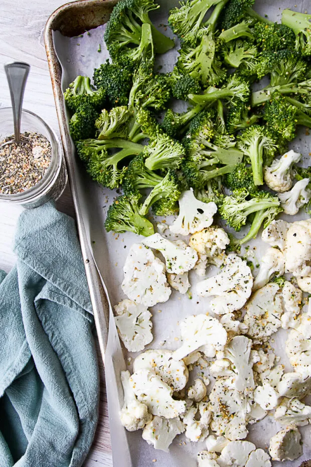 Broccoli and cauliflower ready to roast in the oven on a sheet pan.