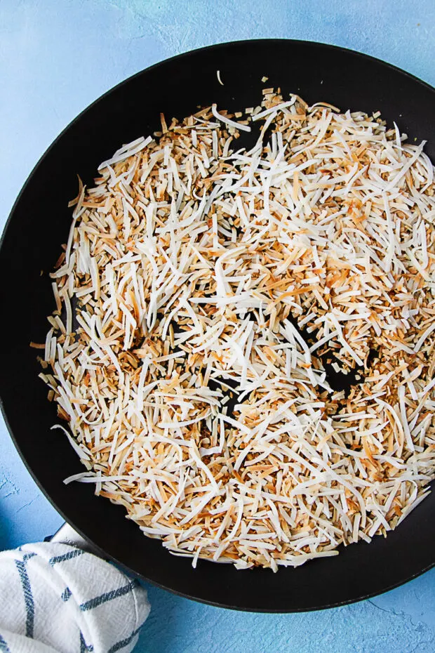A skillet with unsweetened toasted coconut.