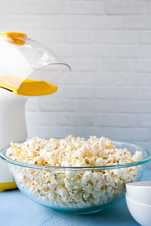 Air popper next to a bowl of freshly popped popcorn.
