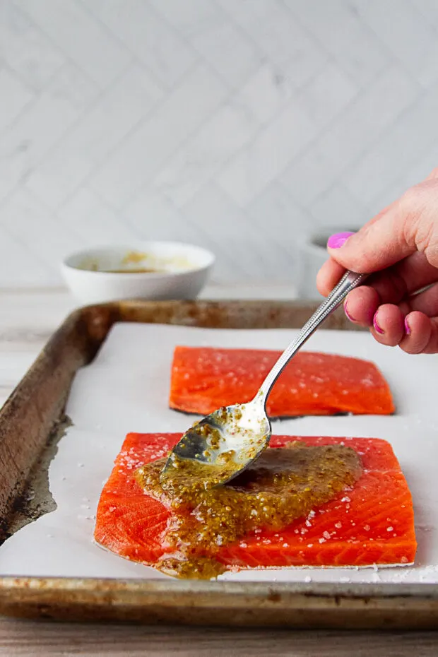 Honey mustard sauce being spread on a salmon fillet.
