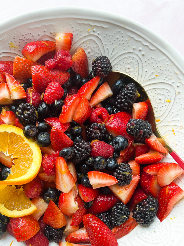 Mixed Berry Salad in a serving bowl garnished with an orange slice.