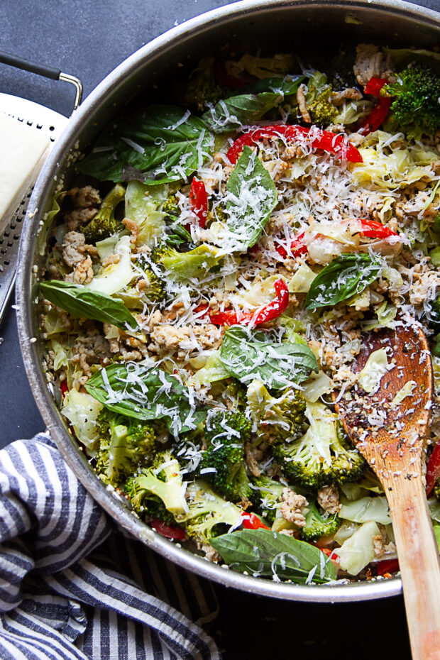 Skillet with Italian Chicken Sausage cooked with vegetables and topped with shredded Parmesan cheese and fresh basil.