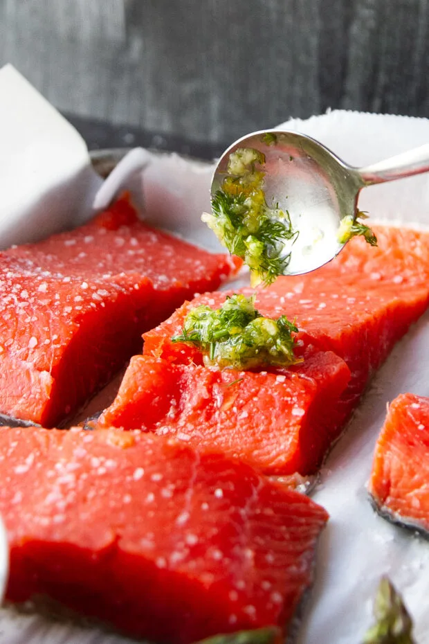 Some of that herby garlic mixture being spread over a salmon fillet