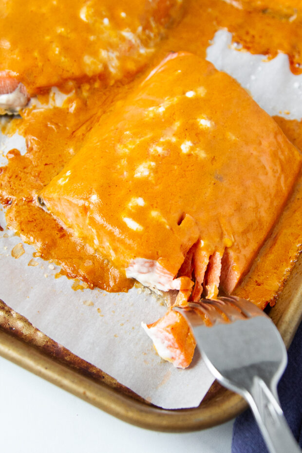 Baked salmon fillets flaked apart with a fork.