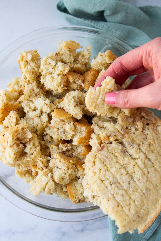 Toasted coconut sponge cake ripped into pieces in a glass bowl.