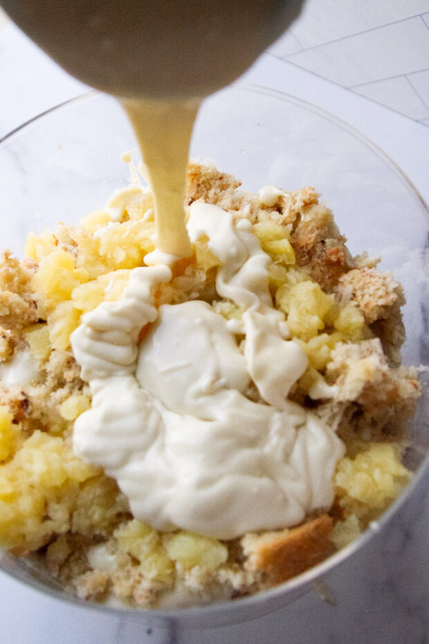 Trifle assembly - coconut custard is added to the dish on top of some crushed pineapple and toasted coconut sponge cake.