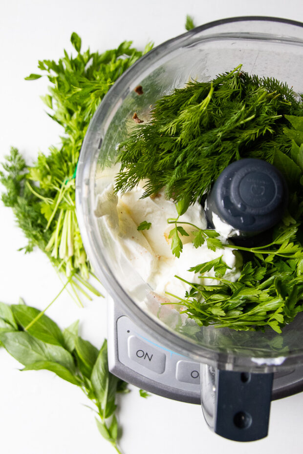 Food processor work bowl containing ingredients for green goddess dip