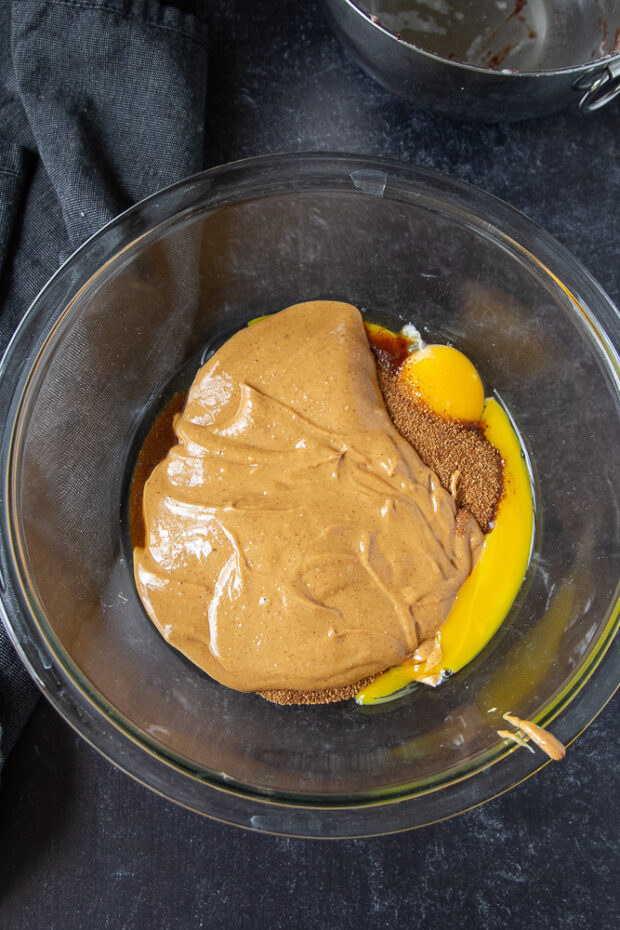 A mixing bowl with eggs, peanut butter, and coconut sugar.