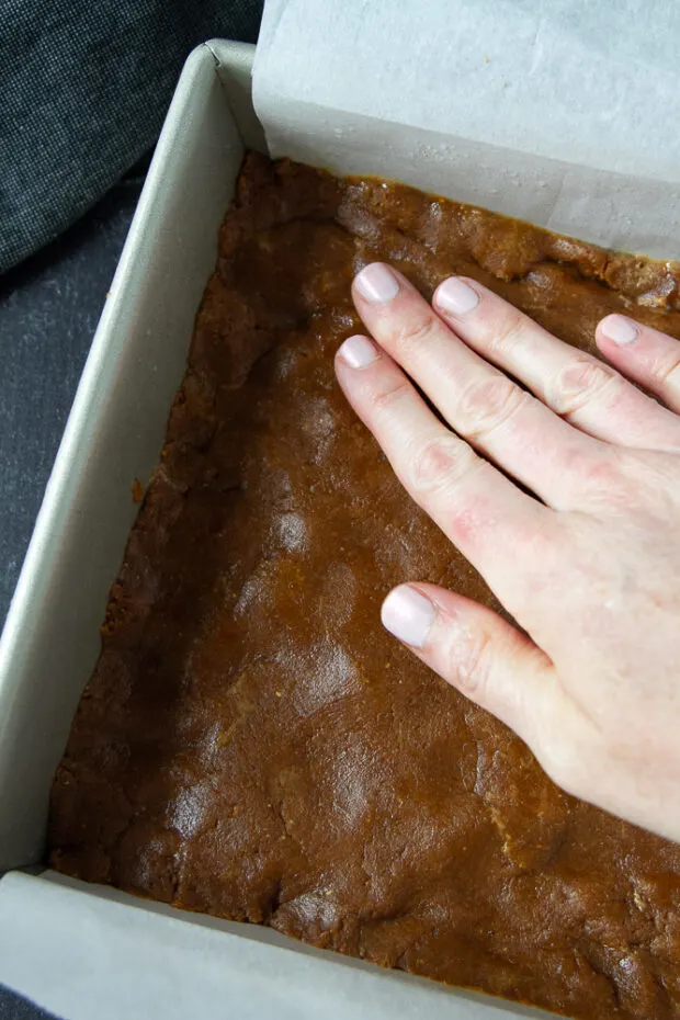 Peanut butter cookie dough layer pressed into a baking pan.