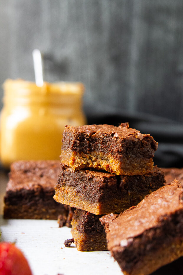 A stack of chocolate peanut butter brownies with a bite taken out of the top one in the stack.