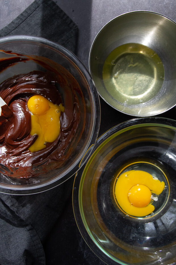 Three bowls -- one containing the melted chocolate/egg mixture, one has egg whites, and one has only egg yolks.
