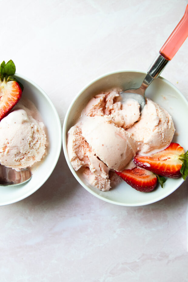 Bowls of the strawberry frozen yogurt with fresh strawberries on the side.