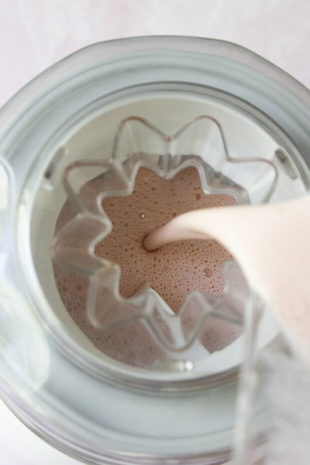 Blended yogurt mixture being poured into an ice cream machine.