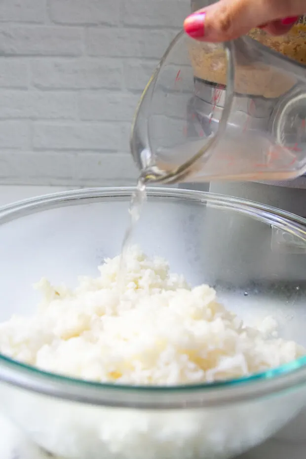 Vinegar dressing being poured over freshly steamed sushi rice.