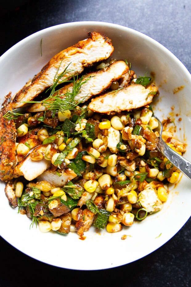 Bowl with sliced blackened chicken and sautéed corn & zucchini.