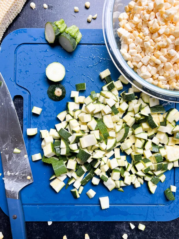 Chopped zucchini and fresh corn in a glass bowl.