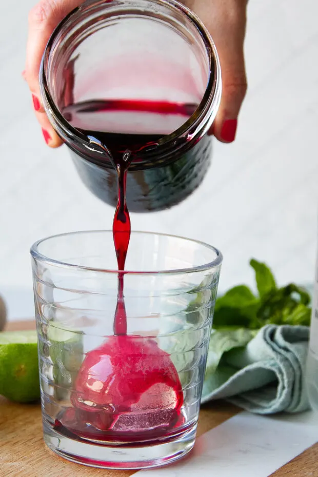 Hibiscus syrup poured over ice in a glass.