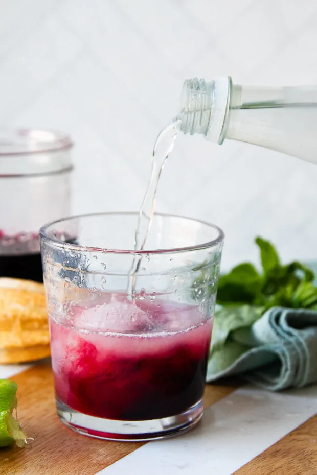 Sparkling water poured into the glass with the syrup & lime juice.